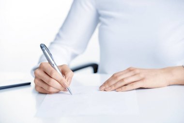 İşkadını'nın el ofis masa başında otururken kalem ve kağıt işareti tutarak yakın çekim çekim.