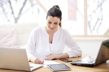 Güzel genç kadın ofis masa bilgisayar başında oturan ve ve bazı evrak işlerini yönetirken yapıyor. Ev ofis. 