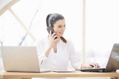 Genç işkadını yapma çağrısı ve ofis masa başında otururken dizüstü bilgisayar kullanarak. Ev ofis.