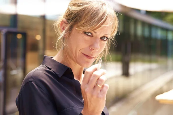 Close-up portait of middle aged woman smoking cigarette while standing outdoor.