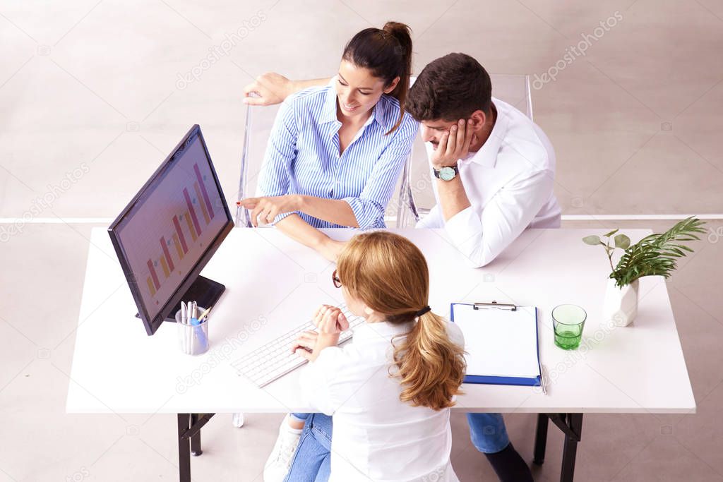 Top shot of investment adviser  businesswoman giving a presentation to a friendly smiling young couple seated at her desk in the office.