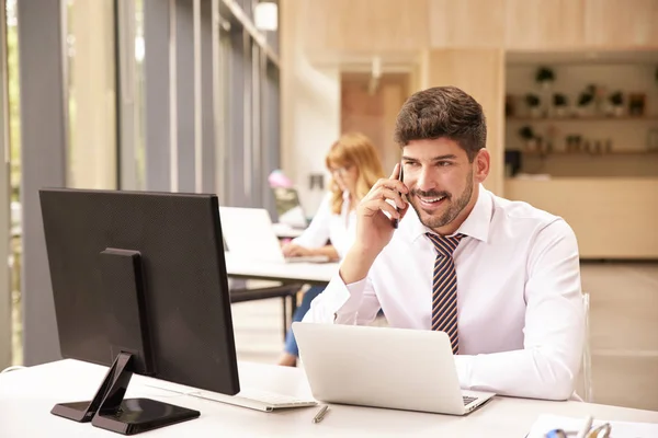 Jovem empresário conversando com alguém em seu celular enquanto — Fotografia de Stock