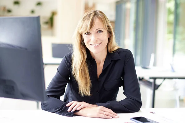 Smiling businesswoman looking at camera and smiling while sittin — 스톡 사진