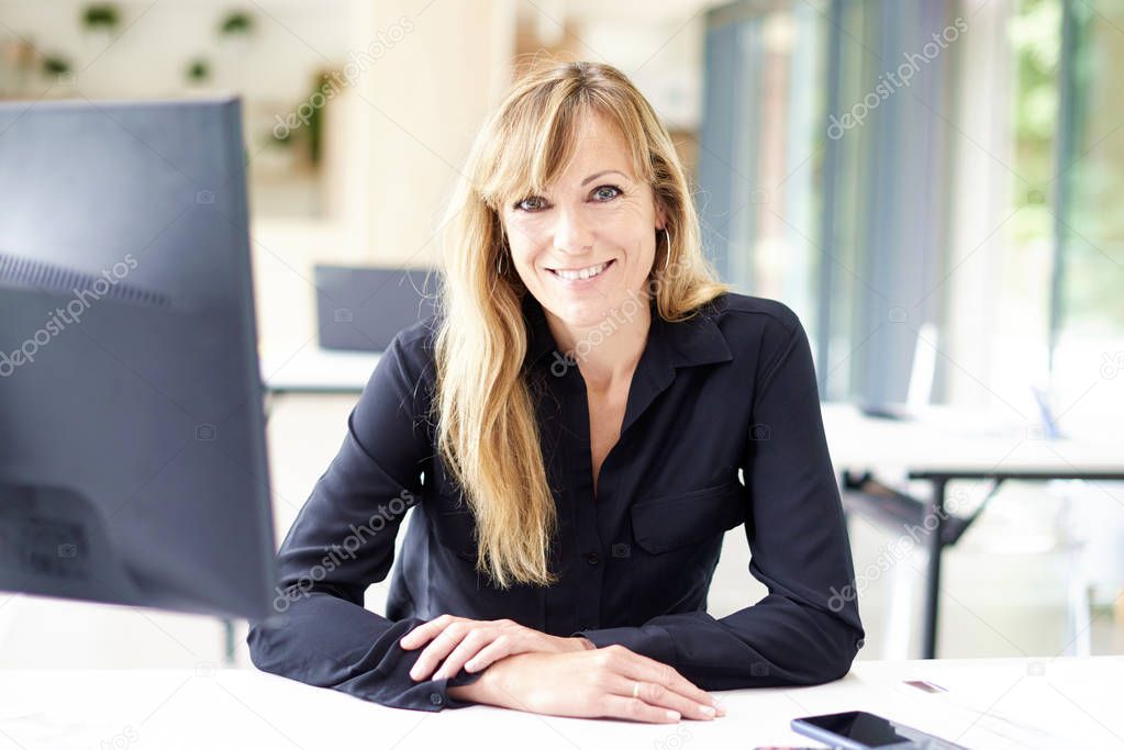 Smiling businesswoman looking at camera and smiling while sittin