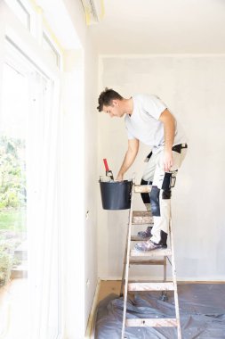 Çadırın duvarını boyayan genç adamın fotoğrafı.