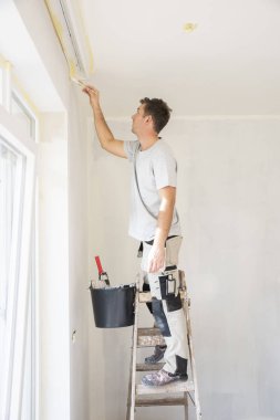 Çadırın duvarını boyayan genç adamın fotoğrafı.