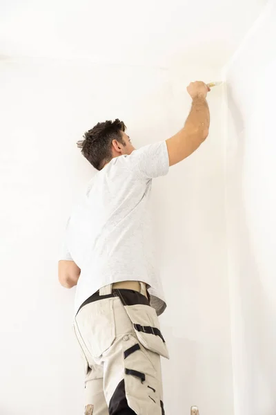 Tiro de jovem pintando a parede do aparmtent — Fotografia de Stock