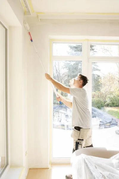 Jovem pintando a parede na casa — Fotografia de Stock