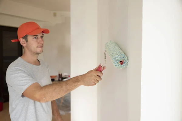 Młody człowiek robi remont mieszkania podczas malowania ściany — Zdjęcie stockowe