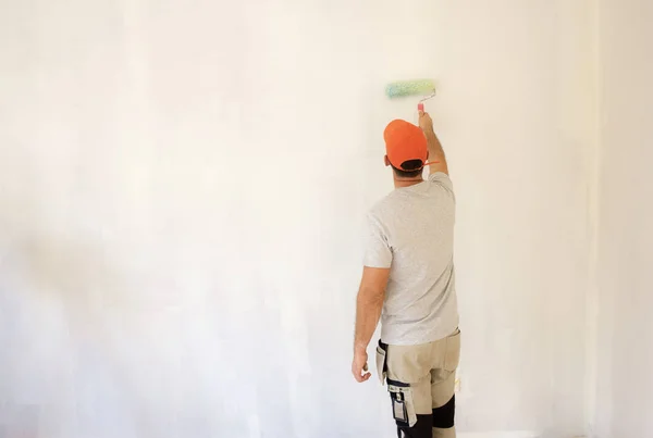 Młody mężczyzna maluje ścianę w mieszkaniu — Zdjęcie stockowe