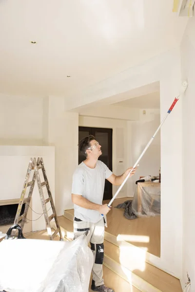 Mladý muž maluje zeď v domě — Stock fotografie