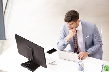 Ofis penceresinde rahatlarken takım elbise giyip kravat takan kendinden emin genç iş adamının portresi.. 