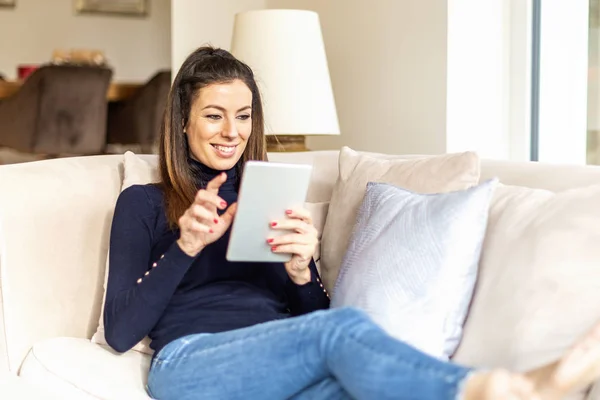 Mulher feliz usando tablet digital enquanto relaxa em casa no s — Fotografia de Stock