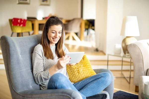 快乐的女人一边在家里休息一边用数码平板电脑 — 图库照片