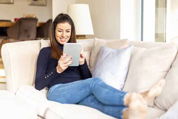 Mulher feliz usando tablet digital enquanto relaxa em casa no s — Fotografia de Stock
