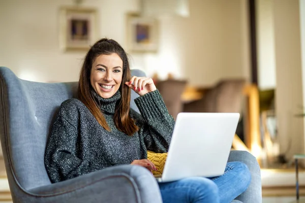 Jovem mulher usando laptop enquanto trabalhava em casa — Fotografia de Stock