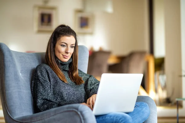 Jovem mulher usando laptop enquanto trabalhava em casa — Fotografia de Stock