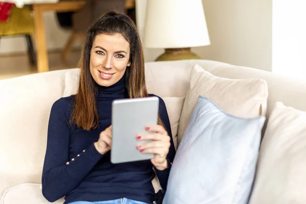 Женщина отдыхает на диване и использует свой цифровой планшет — стоковое фото