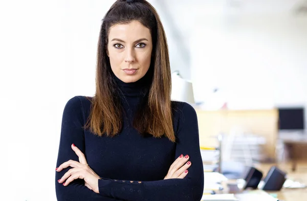 Привлекательная деловая женщина со сложенными руками стоит в офисе — стоковое фото