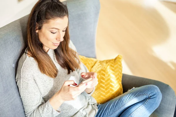 Mujer joven sonriente usando su teléfono celular y mensajes de texto — Foto de Stock