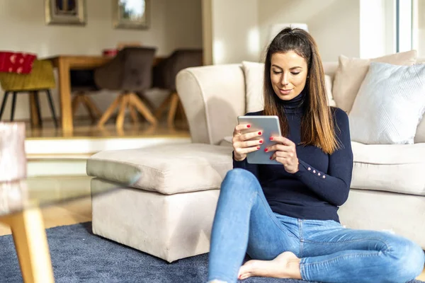 Mulher atraente com tablet digital relaxante em casa — Fotografia de Stock