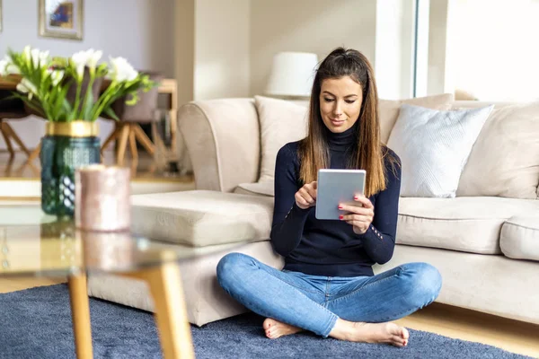 Mulher atraente com tablet digital relaxante em casa — Fotografia de Stock