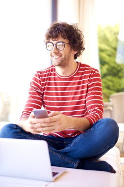 Shot of happy man wearing casual clothes and glasses while text messaging at home. 