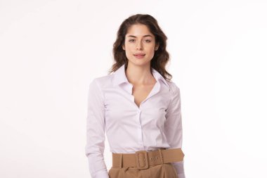 Portrait shot of beautiful young woman wearing white shirt and pants while standing at isolated white background. 