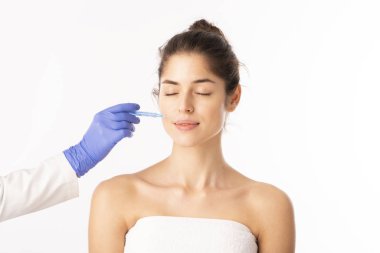Portrait shot of an attractive woman receiving botox treatment for prevention. Isolated on white background. 
