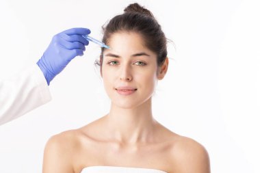 Portrait shot of an attractive woman receiving botox treatment for prevention. Isolated on white background. 