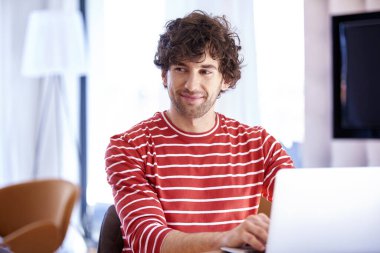 Kendine güvenen ve mutlu bir adamın laptopunun arkasında çalışırken çekilmiş yakın plan fotoğrafı..