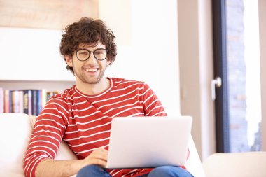 Mutlu adamın kanepeye oturup evde çalışırken dizüstü bilgisayarını kullanması. Merkez Ofis. 