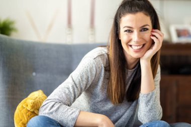 Çekici ve mutlu kadın evdeki koltukta oturuyor. 