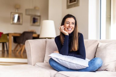 Güzel, gülümseyen kadın evdeki kanepede dinleniyor. 