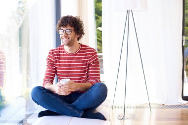 Rahatlamış genç adam evde sabah çayının tadını çıkarıyor.