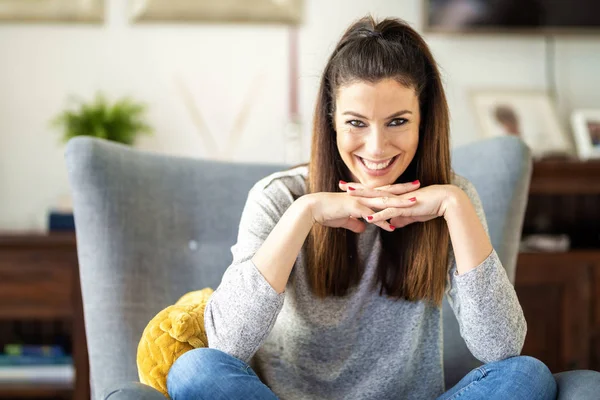 Attraktive und glückliche Frau sitzt zu Hause im Sessel — Stockfoto