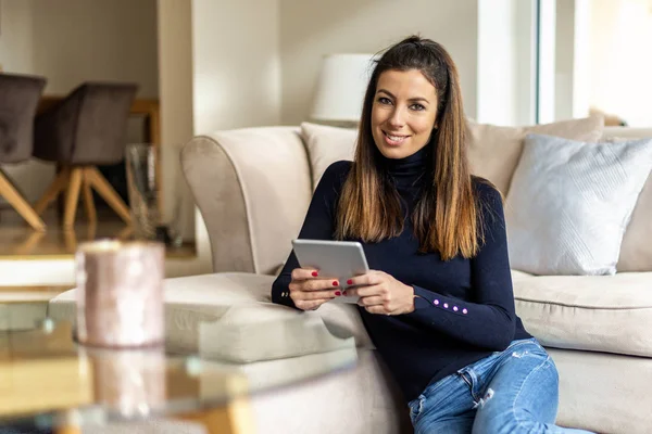 Mulher atraente com seu touchpad relaxante em casa — Fotografia de Stock