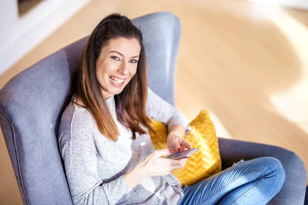Mulher feliz usando seu telefone celular e mensagens de texto enquanto sitt — Fotografia de Stock