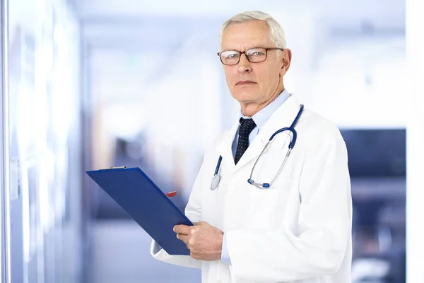 入院中に手にクリップボードを持っている高齢男性医師の肖像画のショット — ストック写真
