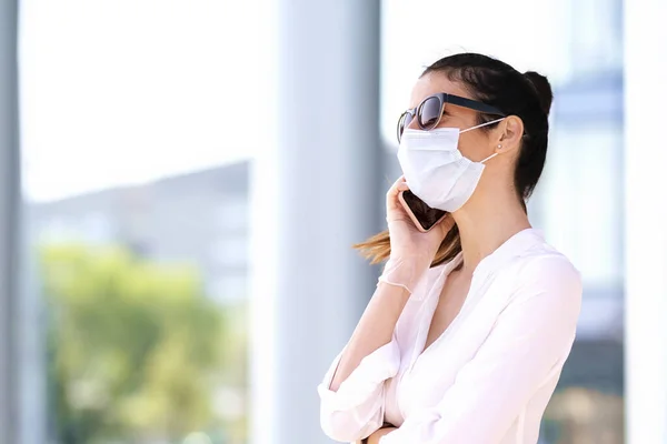 코로나 바이러스가 유행하는 비즈니스 마스크를 휴대폰으로 누군가와 이야기하는 자신있는 여성의 — 스톡 사진