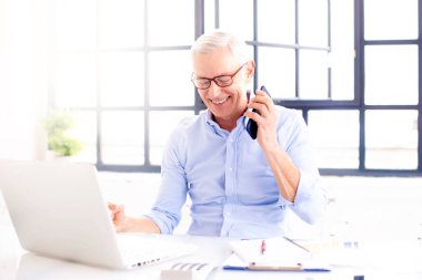 Masada otururken dizüstü bilgisayarda çalışan başarılı iş adamının fotoğrafı. Merkez Ofis.