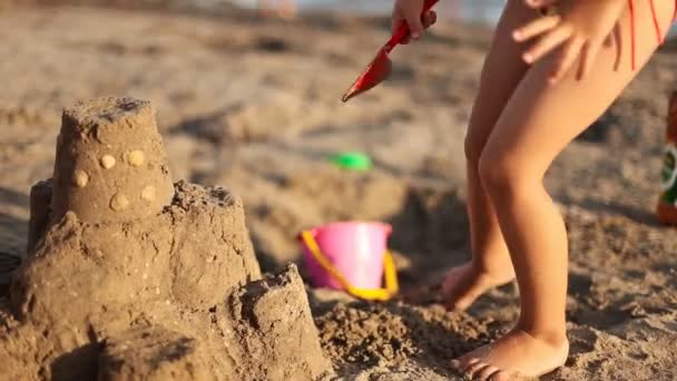 Menina constrói um castelo de areia — Vídeo de Stock