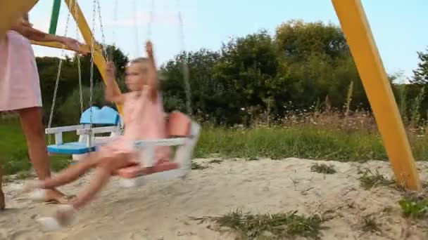 Mom rolls daughter on a swing — Stock Video