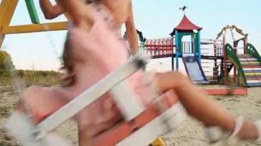 Anne kızı salıncakta alır.