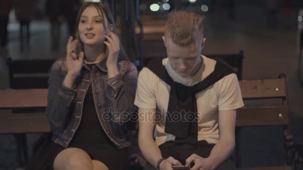 Дівчина говорить, поки хлопець дивиться на телефон — стокове відео