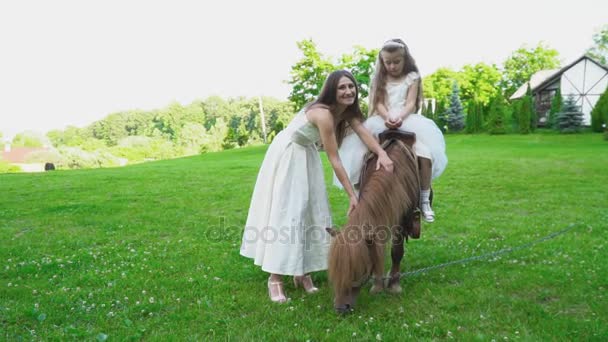 Мать катит свою дочь на пони — стоковое видео