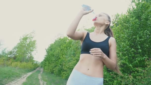 Dziewczyna pije wodę z butelki. — Wideo stockowe
