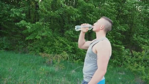 Парень пьет воду из бутылки — стоковое видео