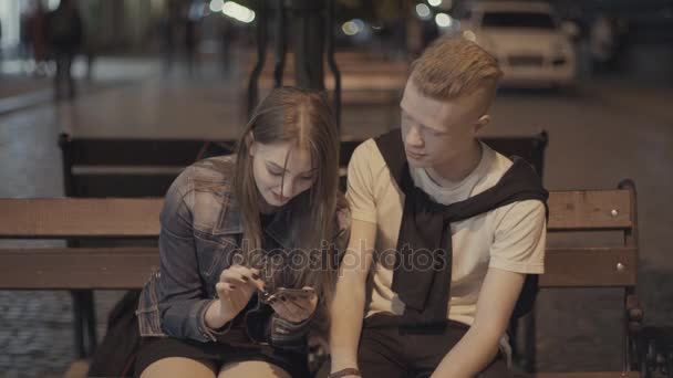 The guy says something to the girl and she looks at the phone — Stock Video