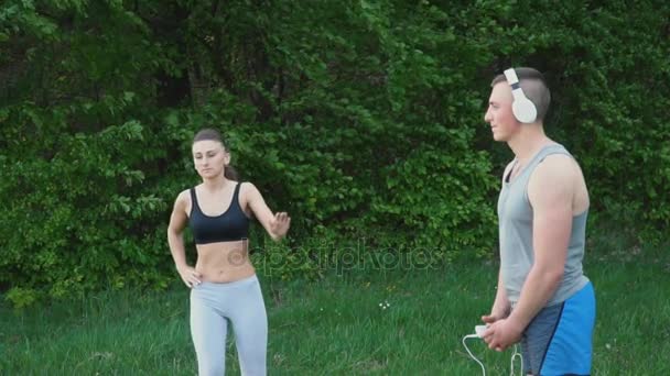 Girl doing a warm-up and a guy wearing headphones — Stock Video